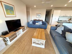 a living room with two blue couches and a flat screen tv at Watermark Apartment 2 - Bring your own linen. in South West Rocks