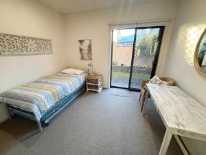 a bedroom with a bed and a sliding glass door at Watermark Apartment 2 - Bring your own linen. in South West Rocks