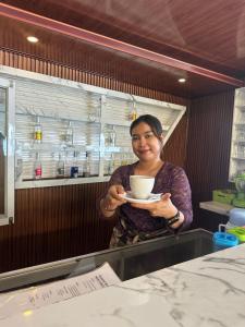 a woman is holding a cup of coffee at Tradisi Villas in Amed +116 photos