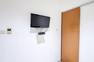 a flat screen tv on a wall in a room at RedDoorz at Residence Bintaro in Mencil
