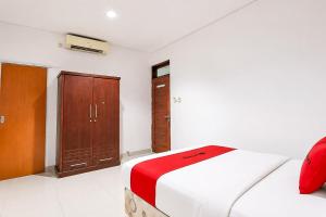 a bedroom with a bed and a wooden cabinet at RedDoorz at Residence Bintaro in Mencil