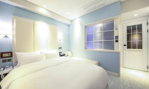 a bedroom with a large white bed and a window at Brooks Hotel Tongyeong in Tongyeong +23 photos