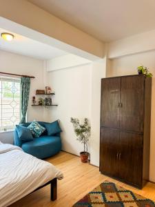 a bedroom with a blue couch and a wooden cabinet at Studio By The Garden in Jawlakhel