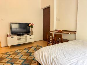 a bedroom with a tv and a table and a bed at Studio By The Garden in Jawlakhel