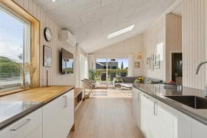 a kitchen with white cabinets and a living room at Spacious Holiday Home On Bogø in Bogø By