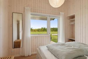 a bedroom with a bed and a large window at Spacious Holiday Home On Bogø in Bogø By