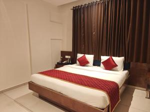 a bedroom with a large bed with red pillows at Hotel Vivank in Kolhapur
