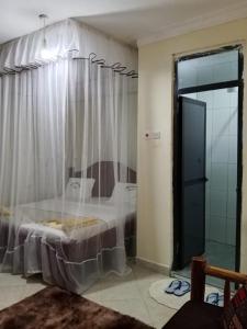 ein Schlafzimmer mit einem Bett mit Vorhang und Glastür in der Unterkunft Luanda Road View Hotel in Luanda