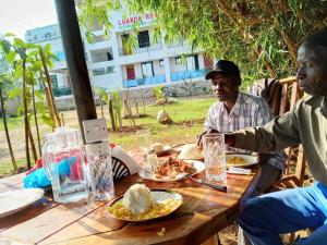 Ein Mann und eine Frau sitzen an einem Tisch mit Essen in der Unterkunft Luanda Road View Hotel in Luanda