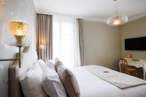 a bedroom with a large white bed with pillows at Villa Edmond Hôtel & Spa - Maison Blanche Bièvres in Bièvres +32 photos