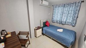 a small bedroom with a blue bed and a desk at แกร็บสลีปโฮสเทล แอร์พอร์ตดอนเมือง in Ban Ko