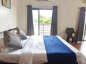 a bed in a bedroom with a large window at Hotel Maurya Regency in Morjim