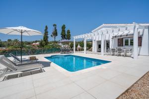 a villa with a swimming pool and an umbrella at Villa de Amigos in Cala en Porter