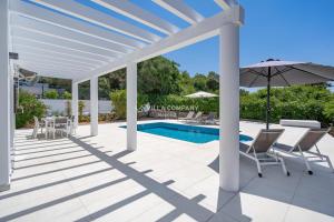 a patio with chairs and an umbrella and a pool at Villa de Amigos in Cala en Porter