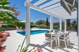 a patio with a table and chairs next to a swimming pool at Villa de Amigos in Cala en Porter
