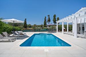a swimming pool with chairs and an umbrella at Villa de Amigos in Cala en Porter