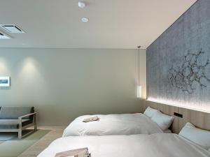 a bedroom with two beds and a chair at らうす餐荘 in Rausu