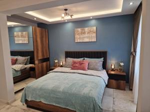 a bedroom with blue walls and a bed with red pillows at Miradi Art Apartment in Stara Zagora