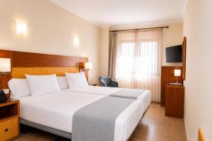 a hotel room with a large white bed and a window at Hotel Córdoba Centro in Córdoba