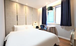 a bedroom with a large white bed and a window at De Lamour Hotel in Tongyeong