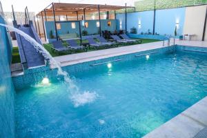 a swimming pool with a waterfall in a hotel at Airport Chalet مزرعة وشاليه المطار in Amman
