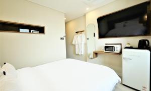 a bedroom with a bed and a flat screen tv at De Lamour Hotel in Tongyeong