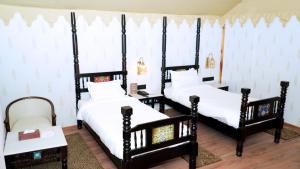 two beds in a room with white sheets at Evoke Rambagh Resort Ayodhya in Ayodhya +28 photos