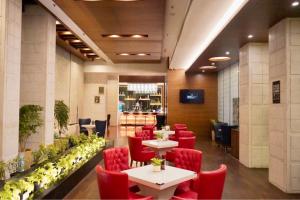 a restaurant with red chairs and tables in a room at Golden Tulip Lucknow in Lucknow