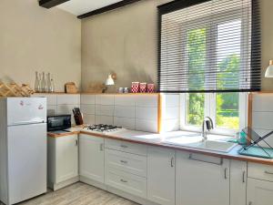 a kitchen with white cabinets and a white refrigerator at La P'tite Bouriane in Le Vigan +9 photos