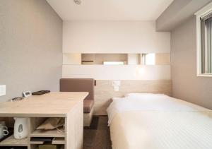 a bedroom with a bed and a desk and a bed sidx sidx sidx at Super Hotel Premier Obihiro Ekimae in Obihiro