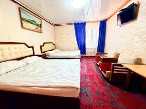 a room with two beds and a desk and a tv at City Hostel & Tours in Ulaanbaatar