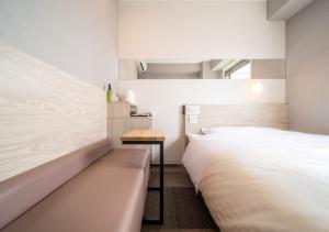 a bedroom with two beds and a bench and a table at Super Hotel Premier Obihiro Ekimae in Obihiro