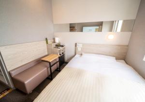 a small room with two beds and a desk at Super Hotel Premier Obihiro Ekimae in Obihiro
