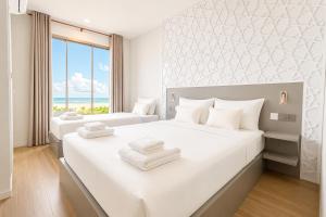 a white bedroom with two beds and a window at Avyanna Gulhi Beach Hotel in Gulhi