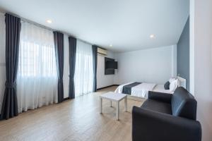 a bedroom with a bed and a couch and a table at Le Nara Residence in Jomtien Beach