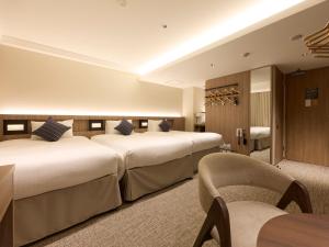 a hotel room with two beds and a chair at Shizutetsu Hotel Prezio Hakataekimae in Fukuoka +91 photos