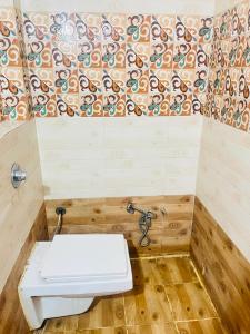 a bathroom with a toilet and a tile wall at Hotel Natraj Palace in Seonī