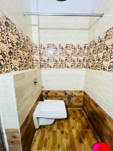 a bathroom with a toilet in a room with wooden floors at Hotel Natraj Palace in Seonī