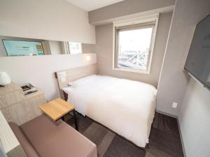 a small bedroom with a white bed and a window at Super Hotel Premier Obihiro Ekimae in Obihiro