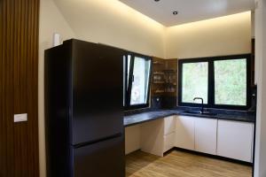 a kitchen with a black refrigerator and some windows at Aries Villa Albania in Vorë