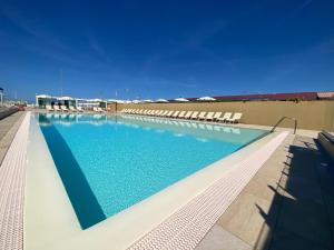a large swimming pool with chairs and blue water at Stabilimento Balneare Città Giardino - Casa Vacanza in Viareggio