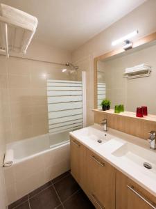 a bathroom with a sink and a tub and a mirror at Hôtel Le Chastellan in Valberg