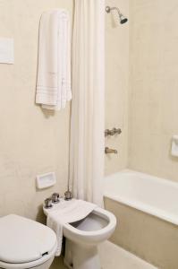 a white bathroom with a toilet and a bath tub at Hotel Presidente in Mar del Plata