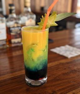 a drink with an orange straw sitting on a wooden table at ECOHOTEL LILI in Puerto Limón