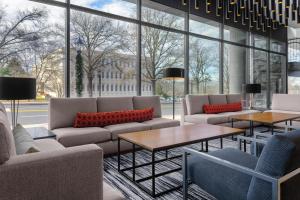 a living room with couches and tables and windows at Hyatt Place Athens Downtown in Athens