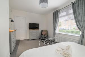 a bedroom with a bed and a tv and a window at Sandyhill, St. Andrews in Fife