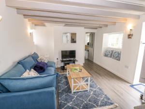 a living room with a blue couch and a table at The Cottage in Stratford-upon-Avon