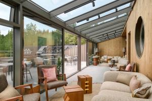 a conservatory with a living room with furniture and windows at Skald Hotel Akureyri, Curio Collection By Hilton in Akureyri