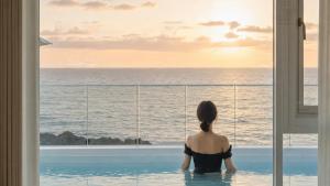 a woman sitting in a swimming pool looking out at the ocean at Donghae Badadam Ocean View Spa Pension in Donghae