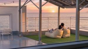 two people sitting on a balcony looking out at the ocean at Donghae Badadam Ocean View Spa Pension in Donghae